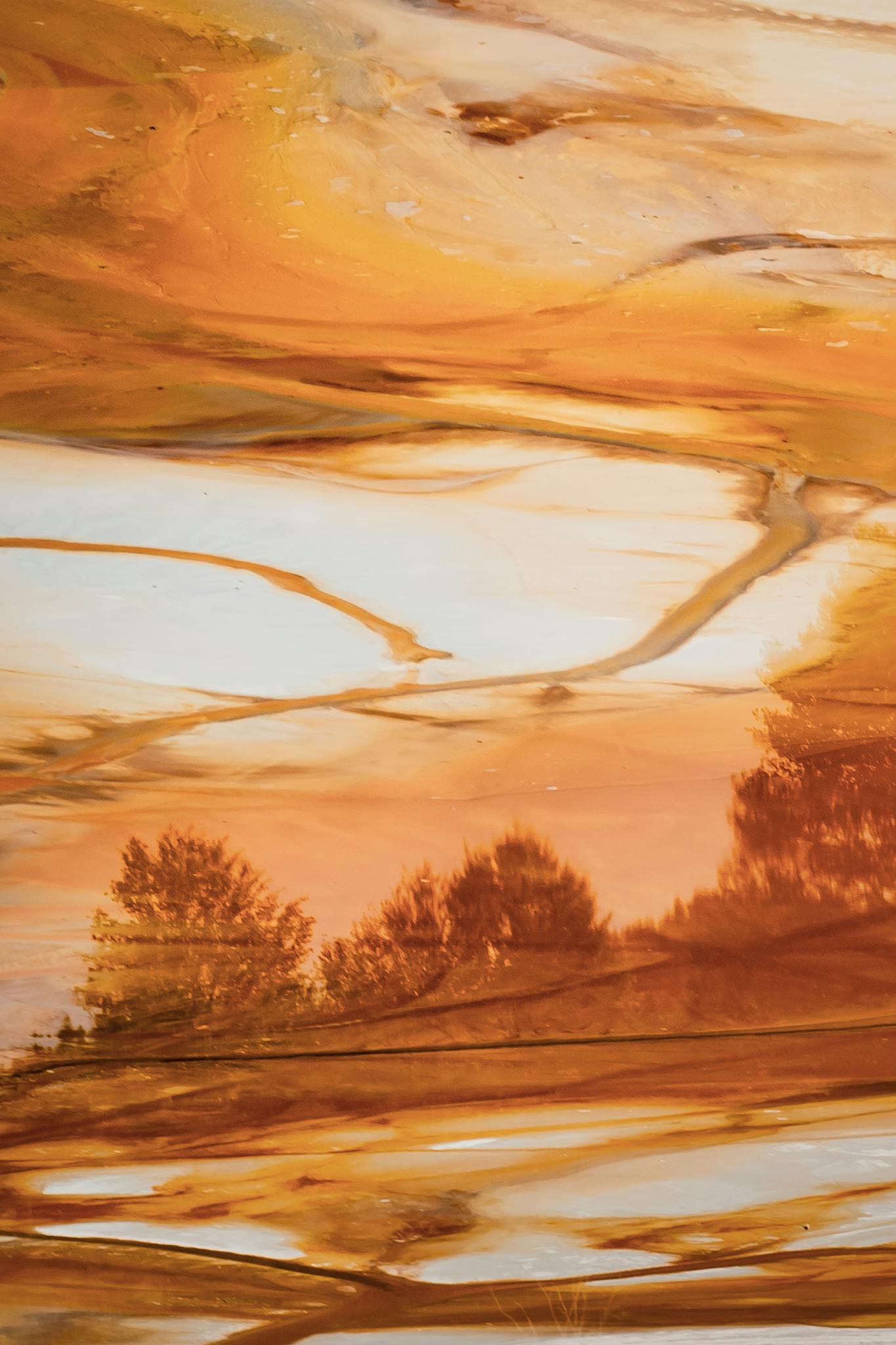 Orange and marbled abstract landscape art with tree reflections, evoking a sunset or fall scene.